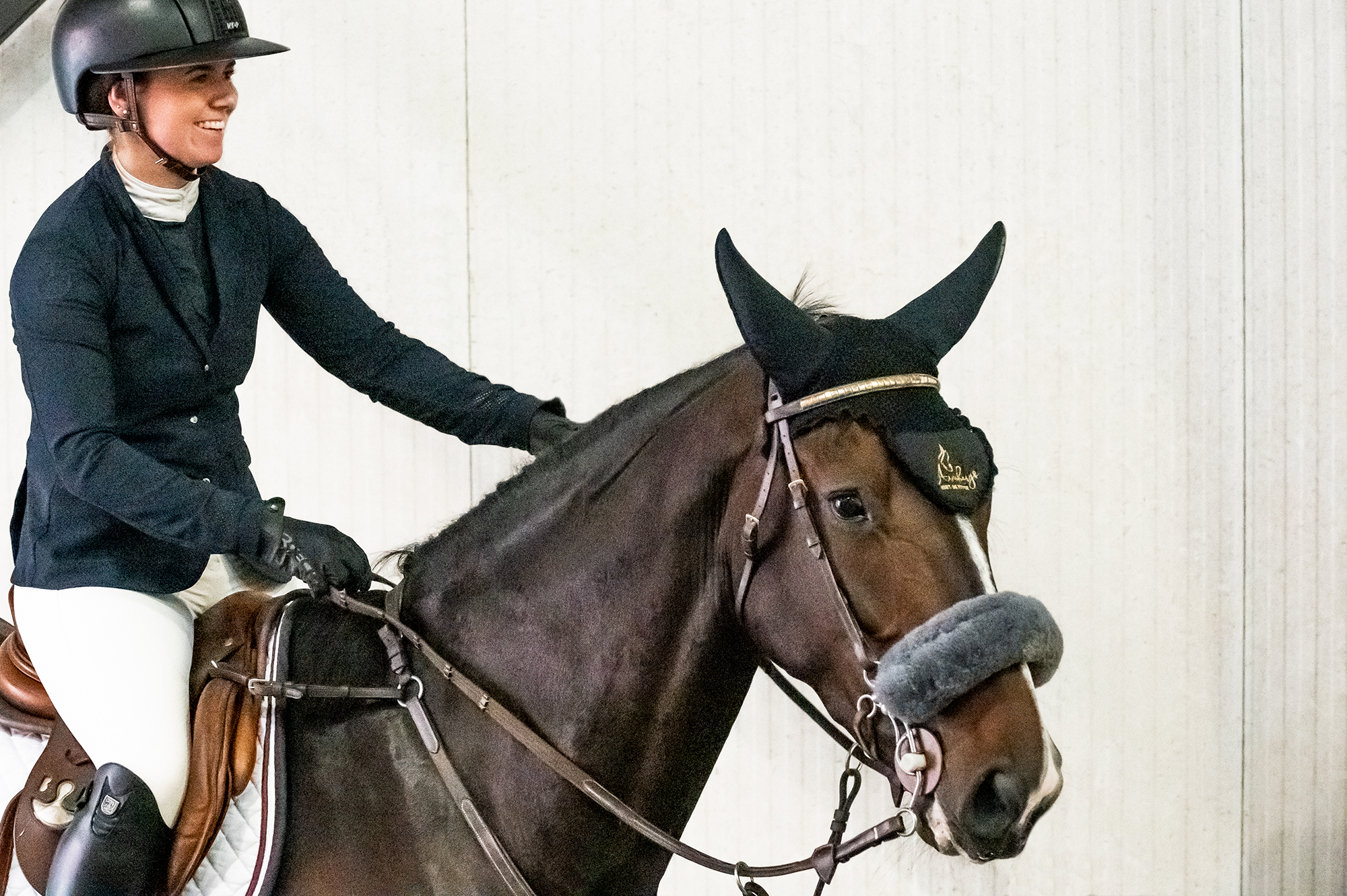 Solveig Fotland Newermann sitter på hesten sin. Hun smiler.