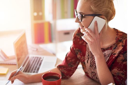 Jente sitter i telefonen foran PC.