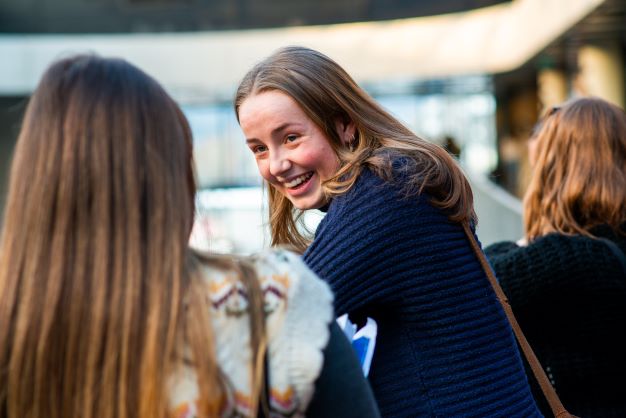 Smilende elev i dialog med annen elev