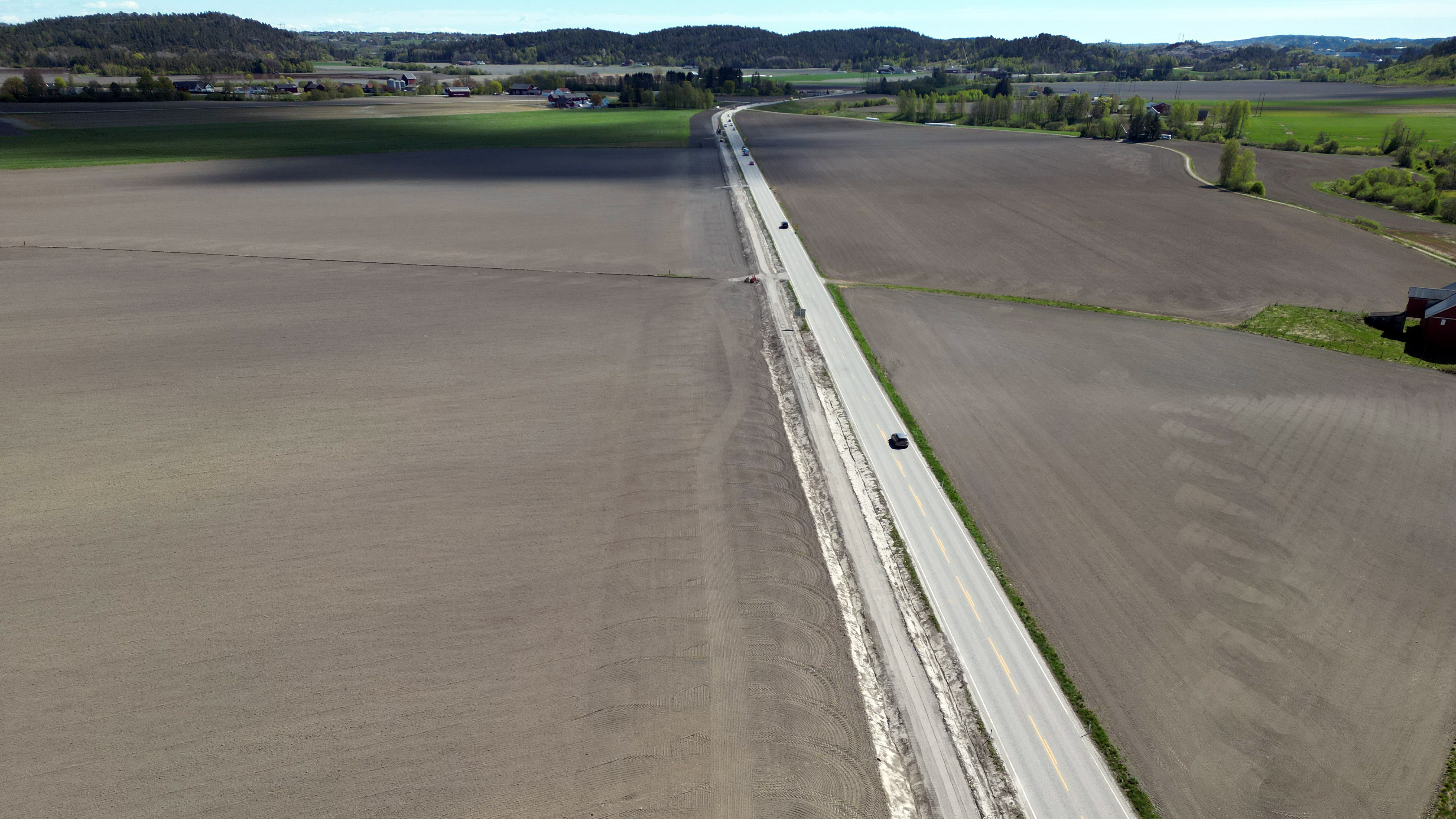 Bilde av Bispeveien fra drone. Viser nysådde jorder og Bispeveien i retning Tønsberg
