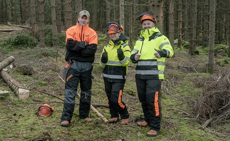 Tre elever med hjelm i skogen