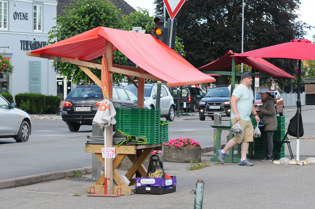 Foto av torvboder på Teie med trafikk i bakgrunnen