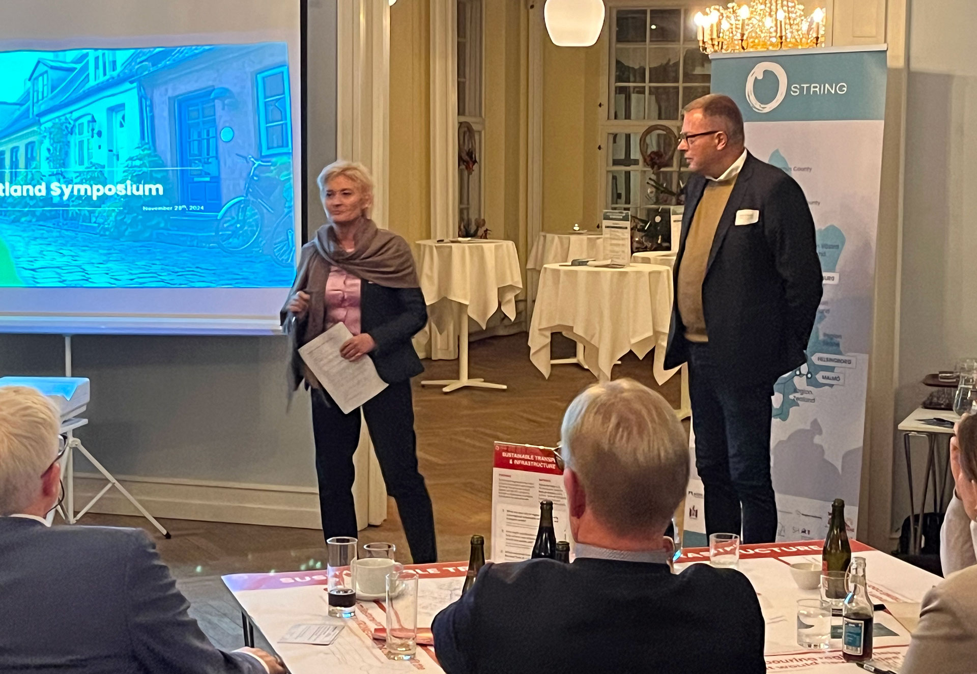 To personer holder tale foran forsamling