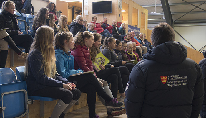 Ungdommer og deres foreldre på tribunen i ridehall