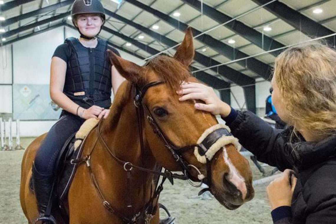 Hest og to elever i ridehall