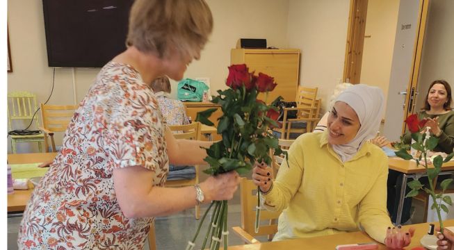 Bilde fra Midtløkken aktivitetshus. Elev får rose av ansatt.