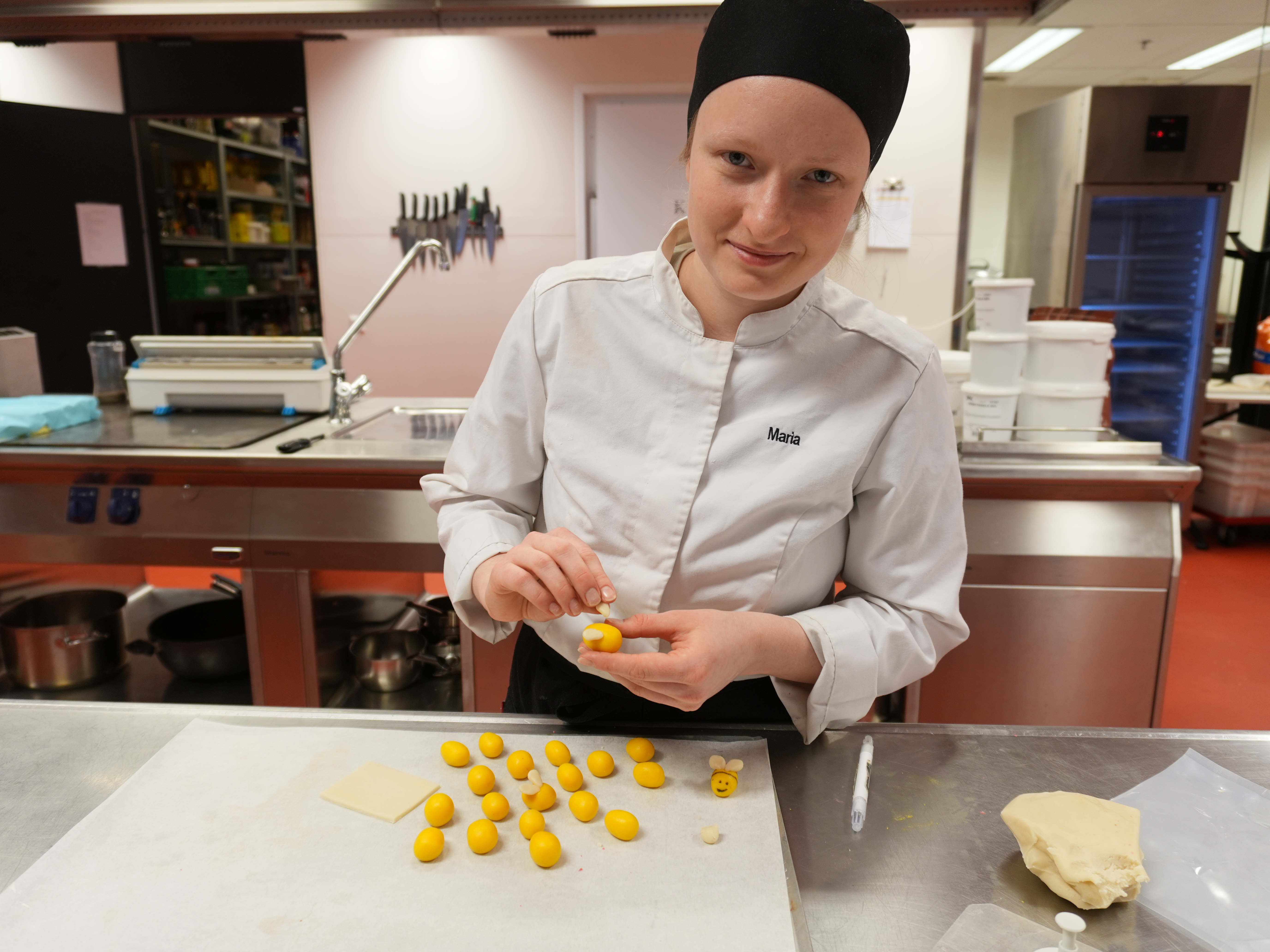 Bilde av ung kvinnelig baker og konditor som lager dekorasjoner av marsipan.