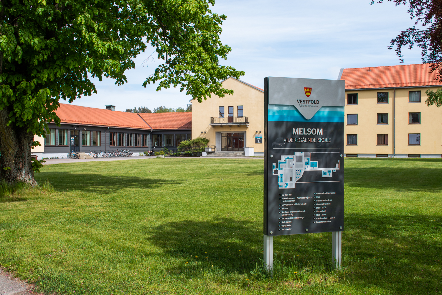 Internatbygget med grønn plen foran og områdeskilt