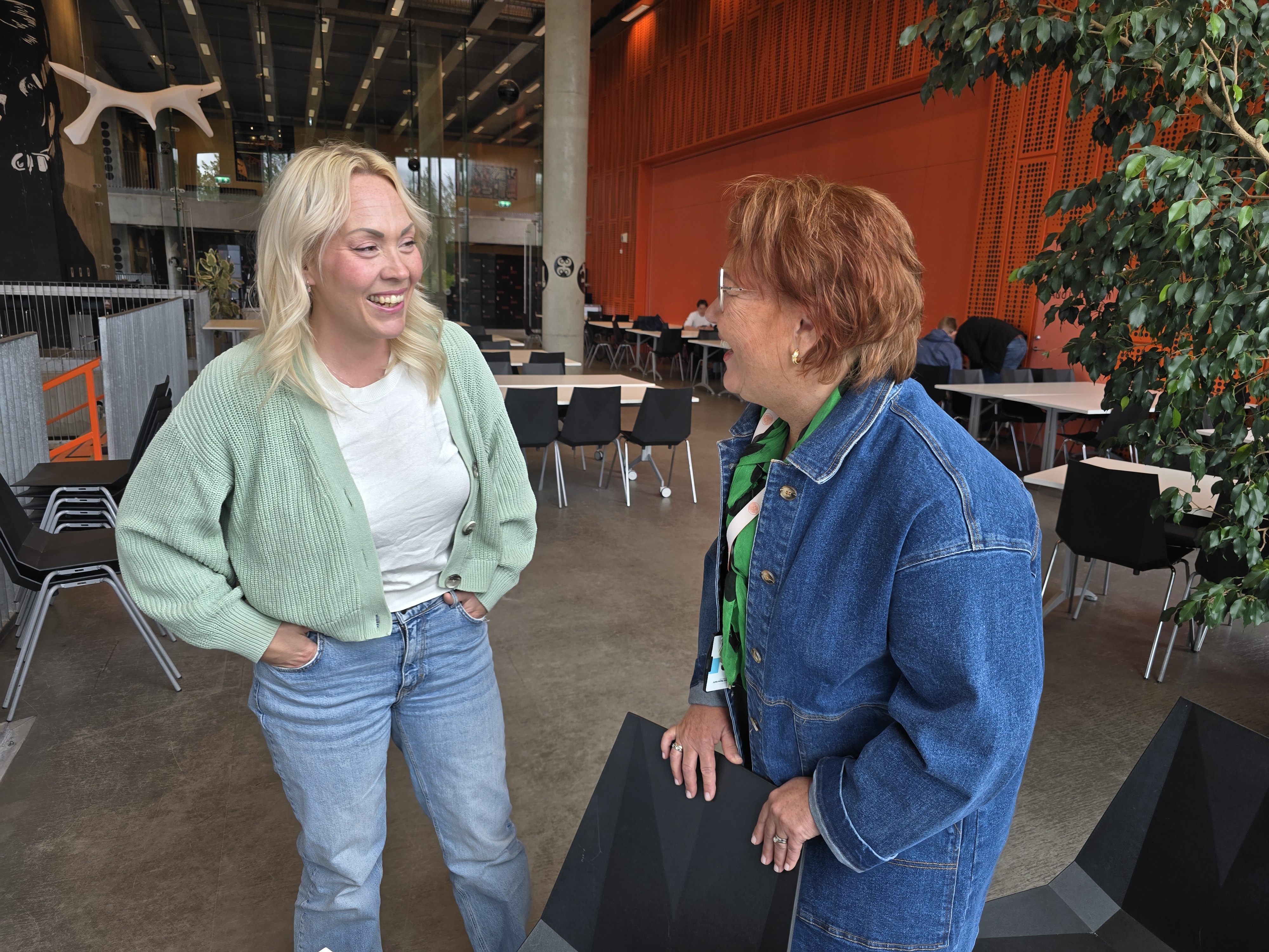 Voksenelev og lærer på skolen, de ser på hverandre og ler.