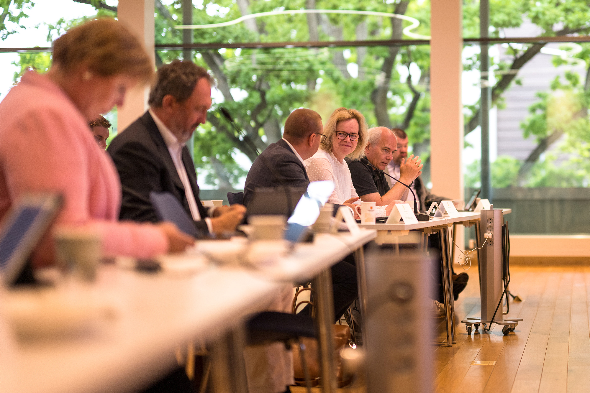 Bilde av flere mennesker i et møte som sitter og følger med.