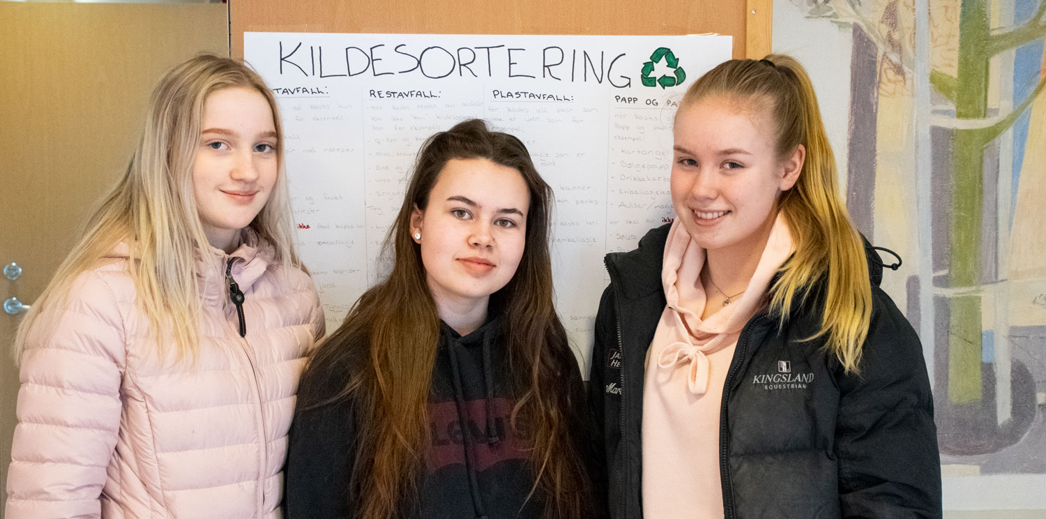 Tre elever foran en kildesorteringsplakat