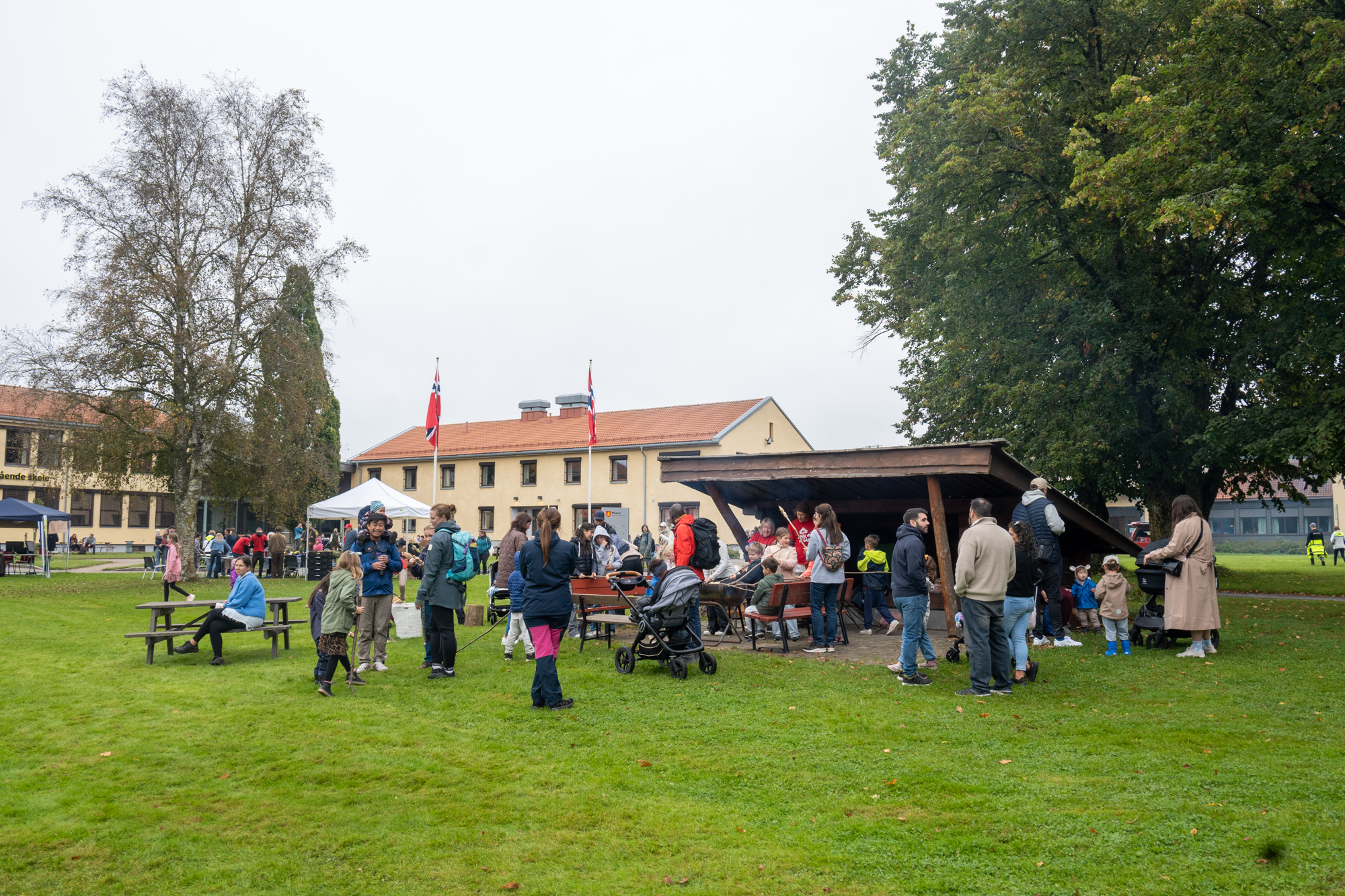 Familier på plen foran skolebygg