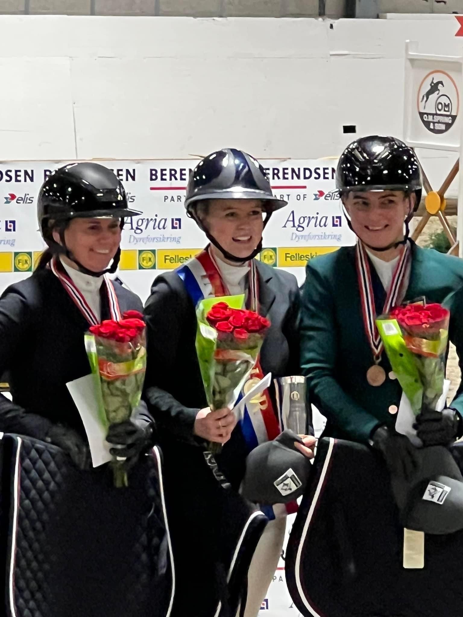 Tre kvinnelige ryttere med medaljene sine og rosebuketter
