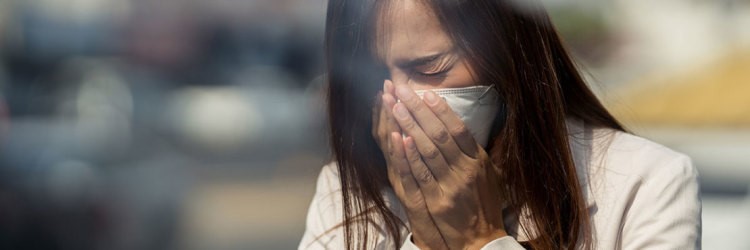 Kvinner nyser inn i munnbind hun har på seg