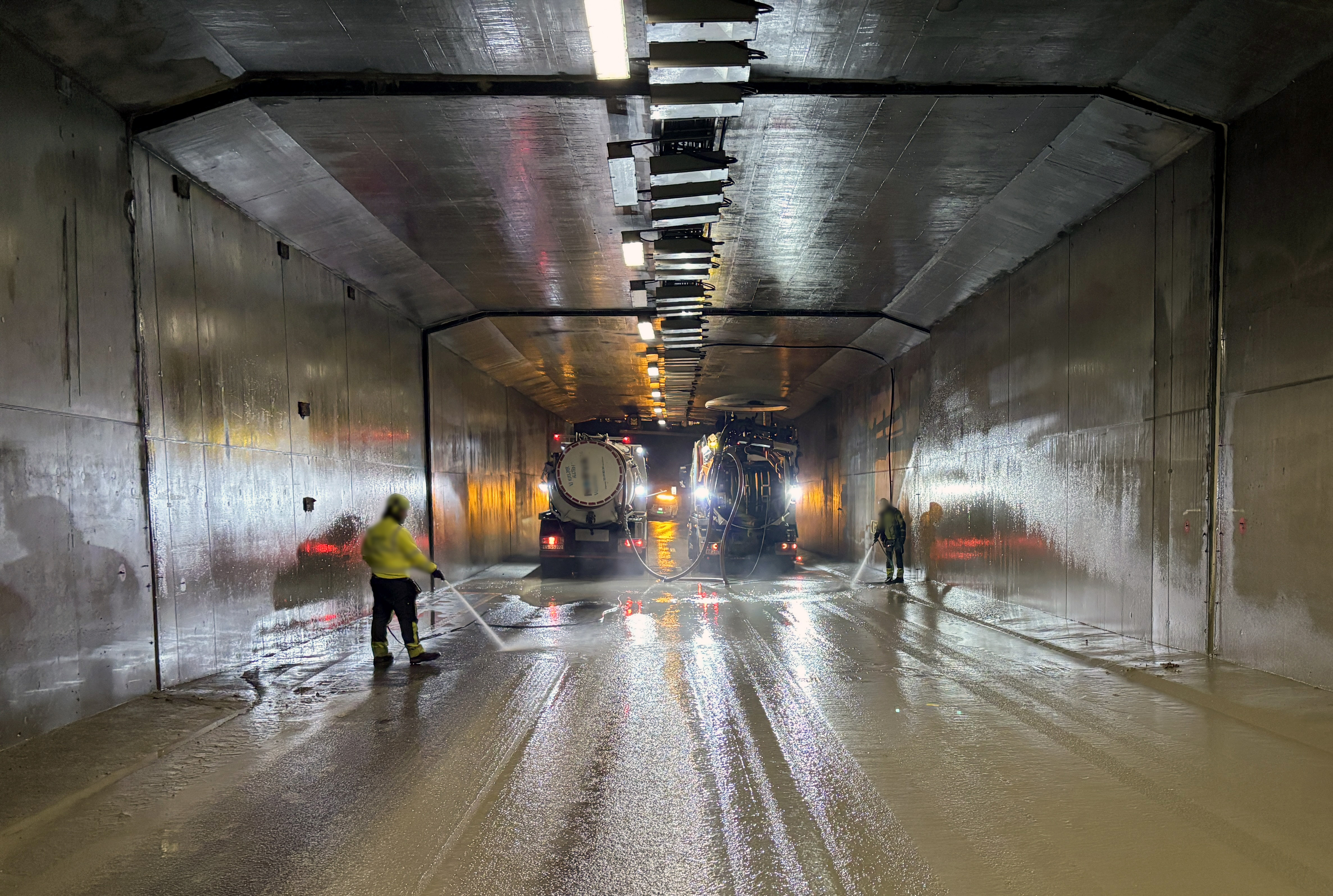Inne i tunnelen der det jobbes med å spyle og samle sammen sementmassene som har rent utover veibanen.