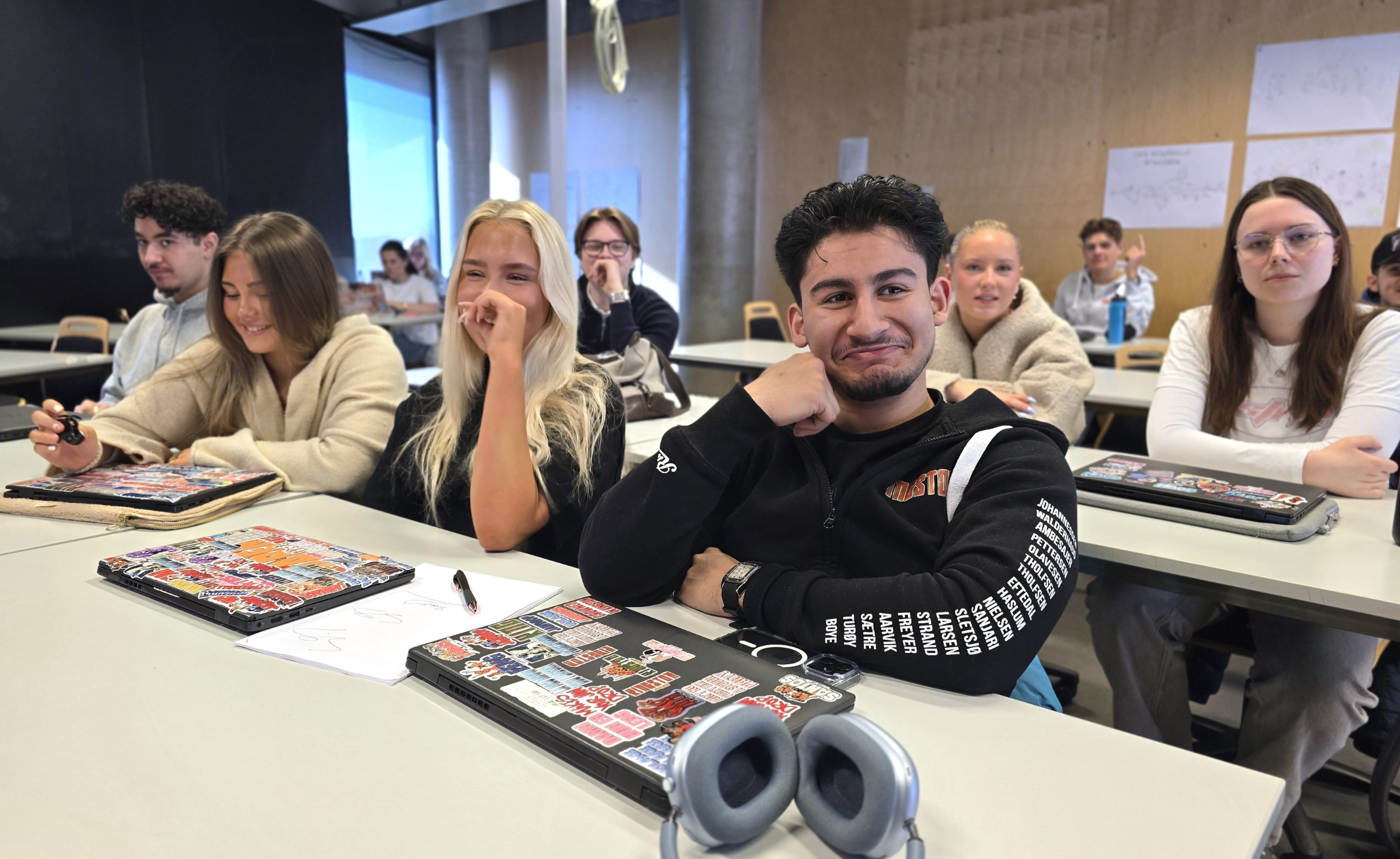 Elever som sitter ved pulter, smilende.