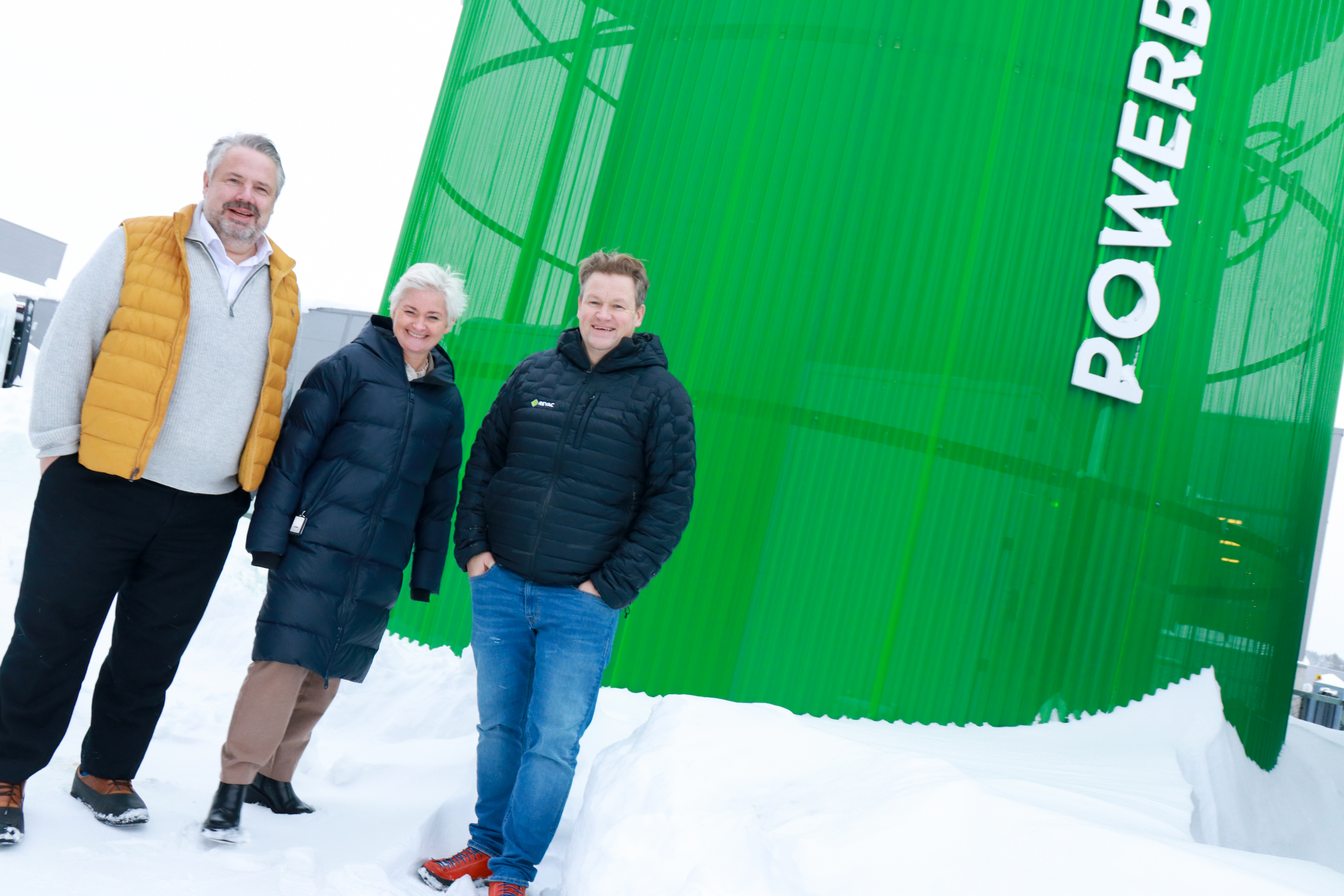 Tre personer står foran en grønn tank