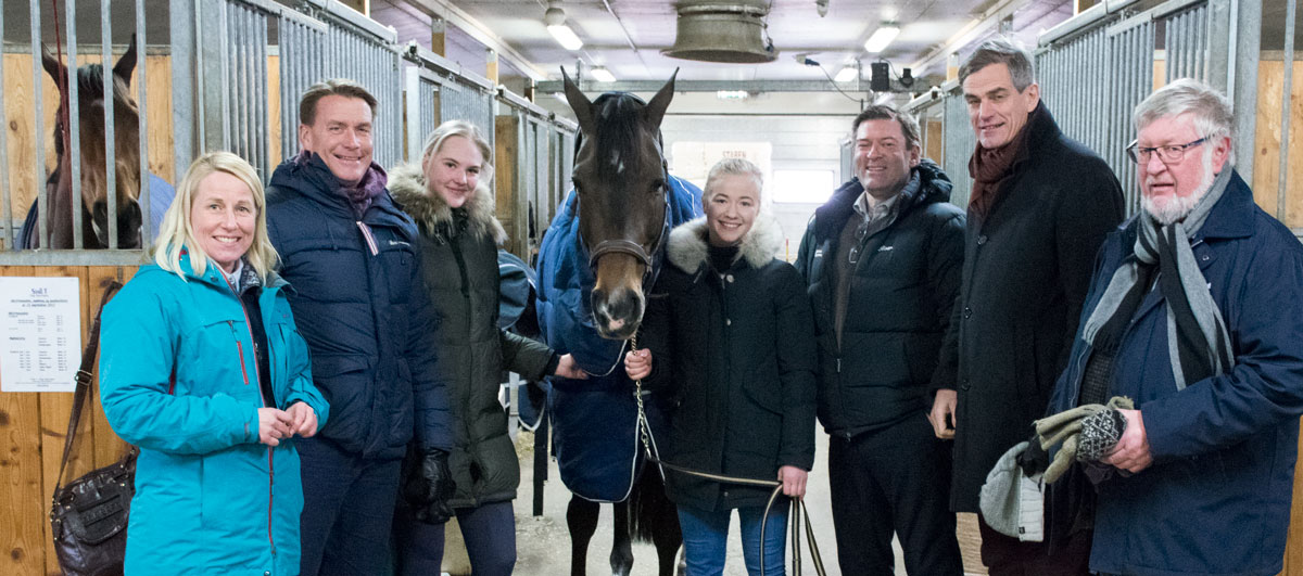 Rektor, politikere og elever rundt en hest i en stall