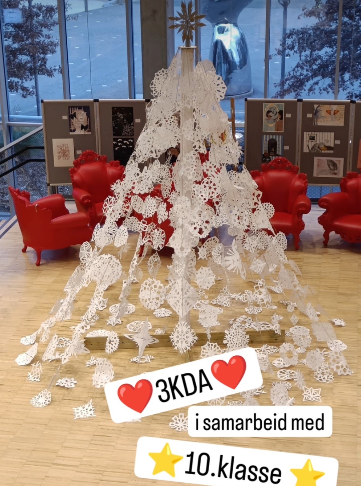 Stort juletre i hvitt papir står i skolens aula.