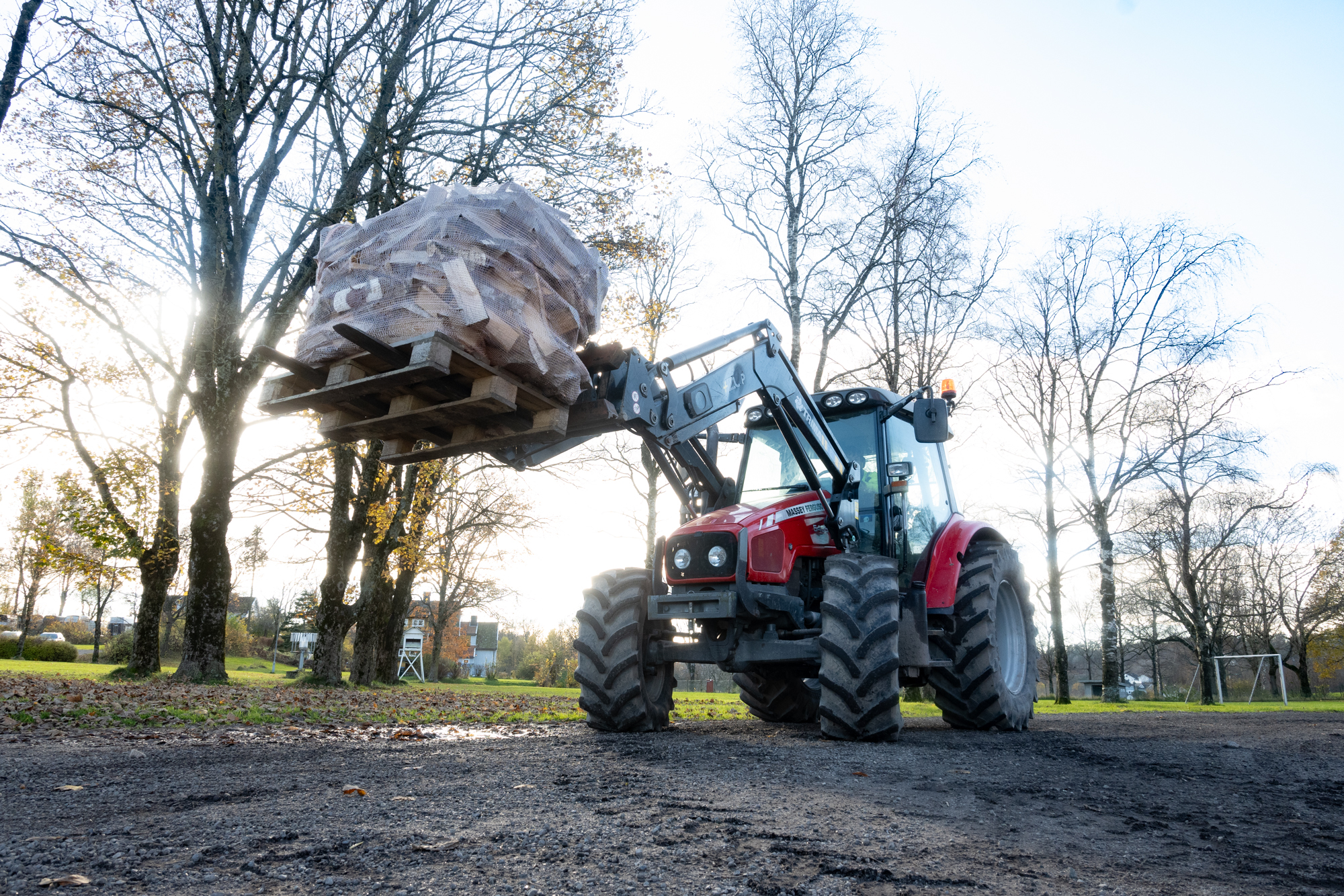 Traktor med en stor sekk med ved på gaffelen