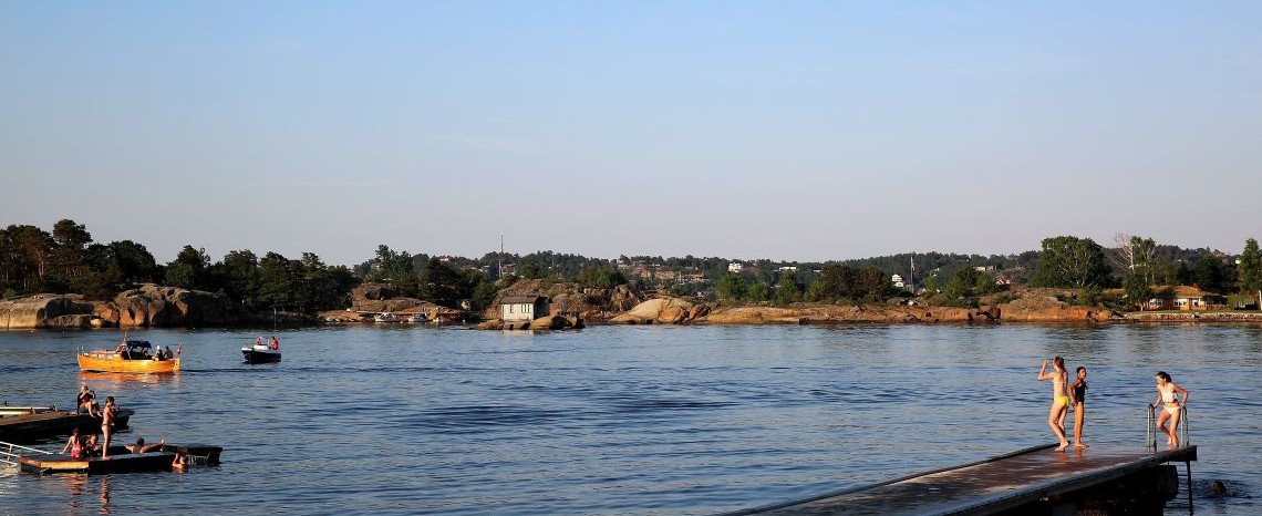 Sommer i Vestfold. Bildet er tatt ved vannet. Barn som bader og båter på vannet.
