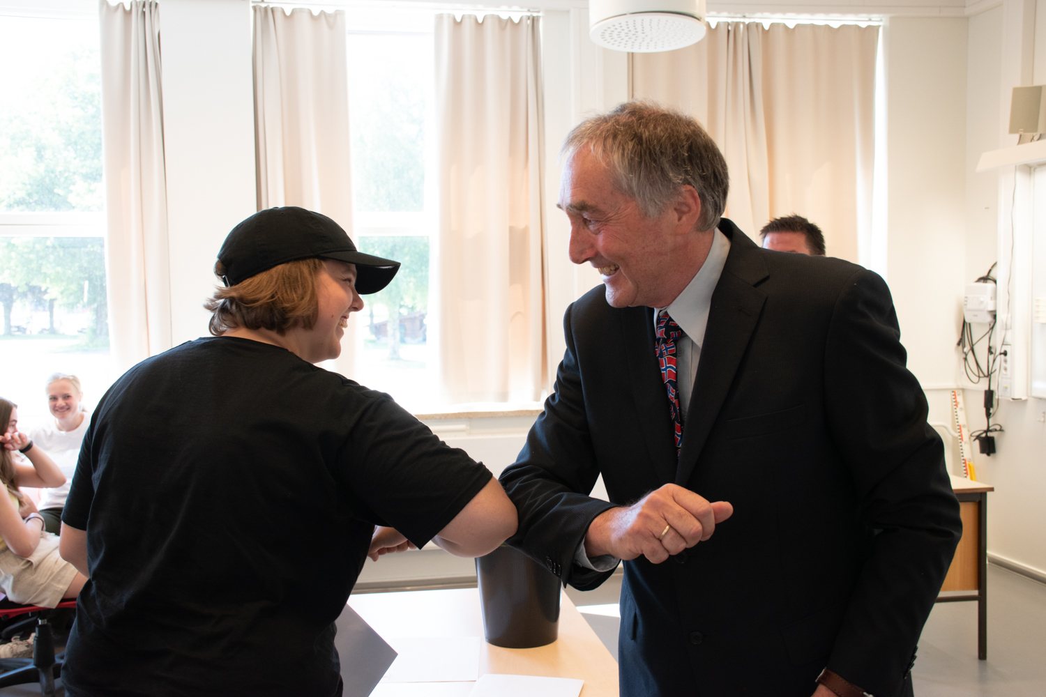 Elev og lærer "albue-hilser" på hverandre