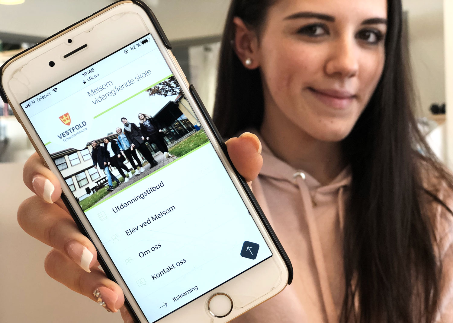 Elev viser fram en mobiltelefon som viser nettsiden vår på skjermen