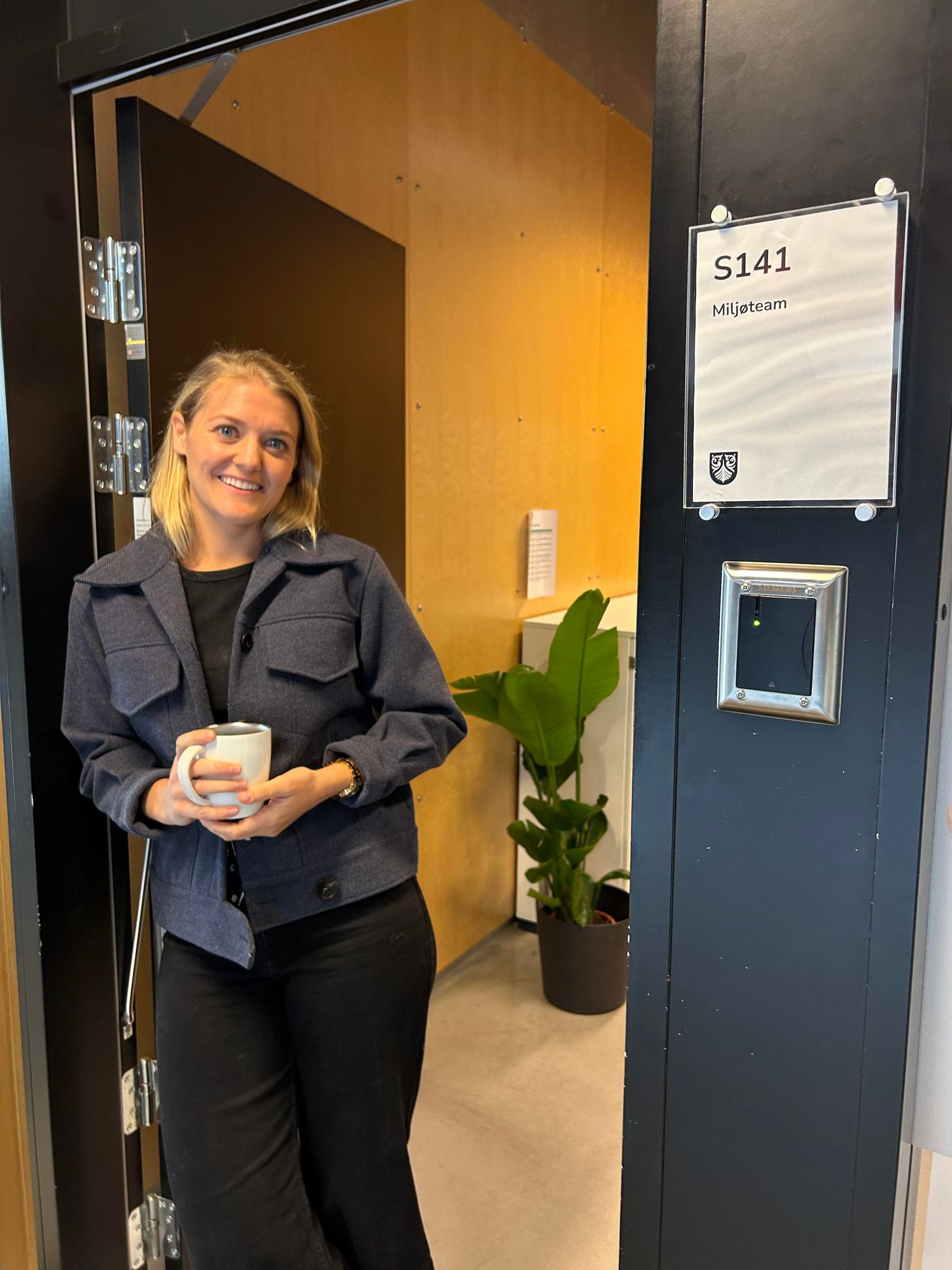 Mathilde (miljøarbeider) står i døra og smiler