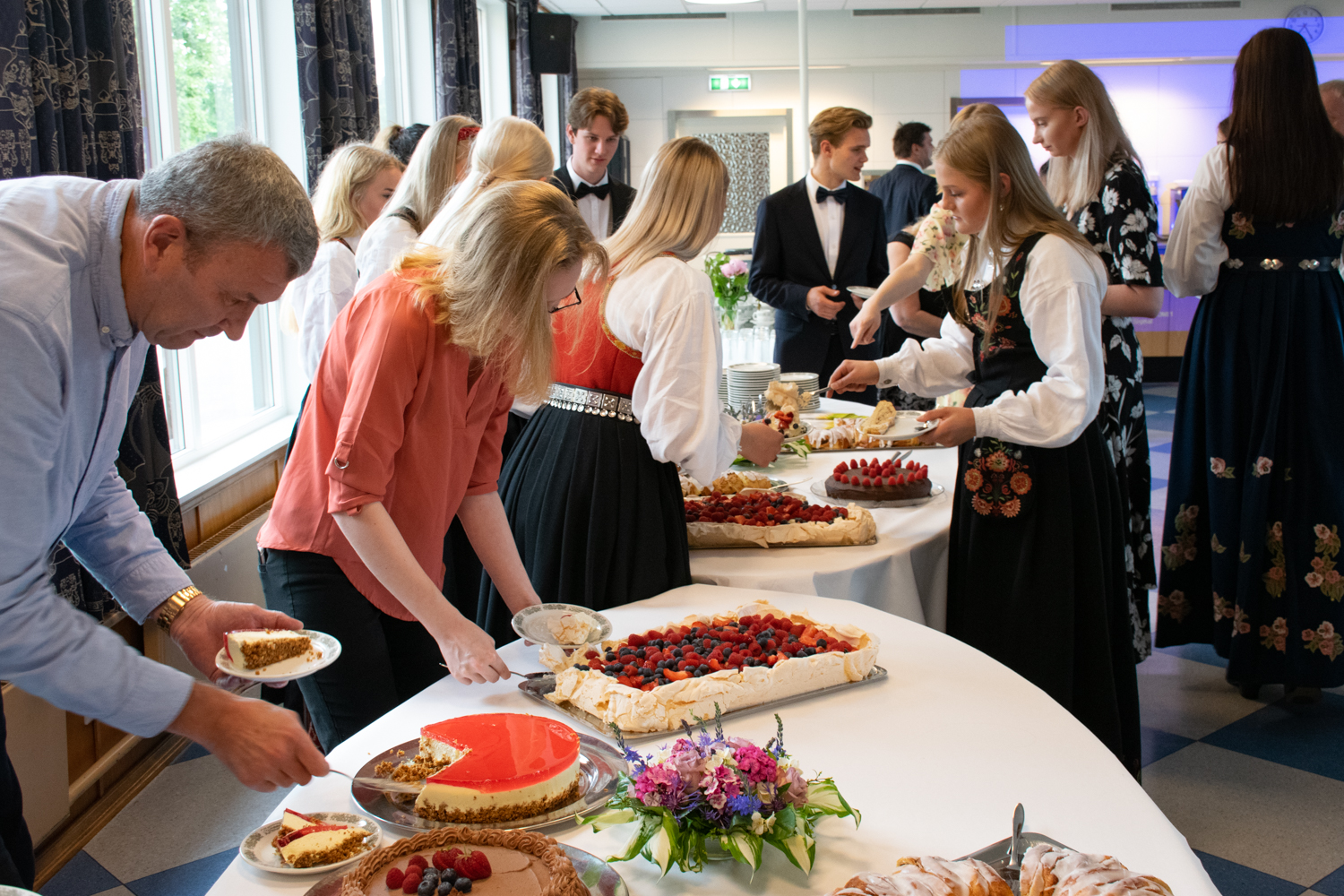 Elever og foresatte forsyner seg med kakestykker fra et langt kakebord med masse kaker
