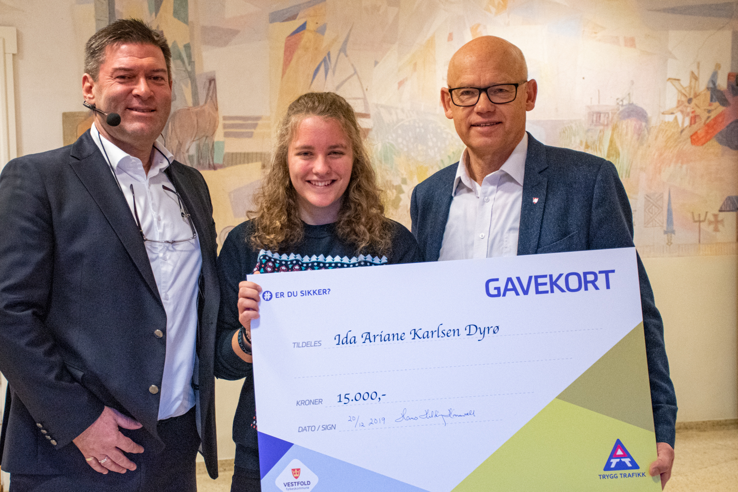 Elev holder en stor utgave av et gavekort. Rundt, står rektor og leder for samferdselsutvalget.