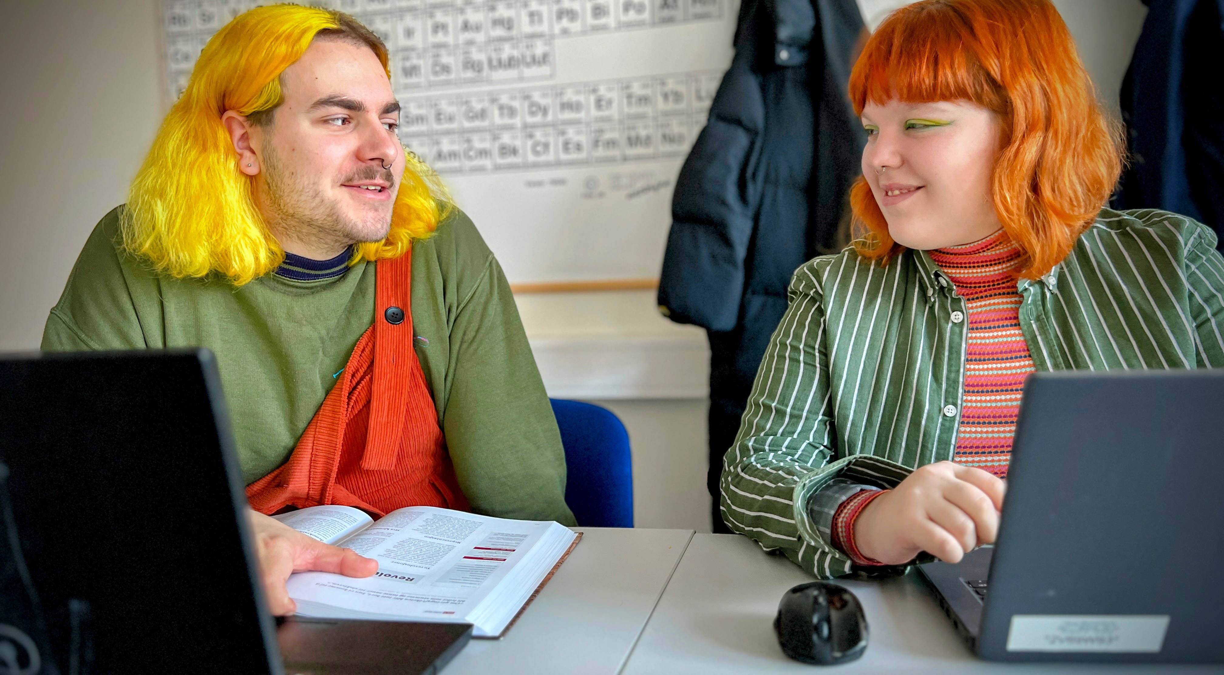 Bilde av to elever som leser historie og skriver på PC.