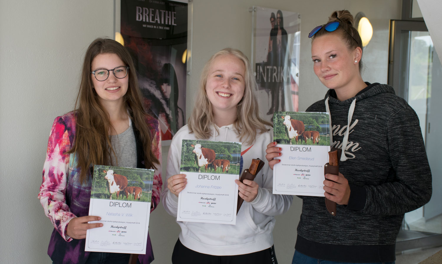 Tre elever viser fram diplomene sine