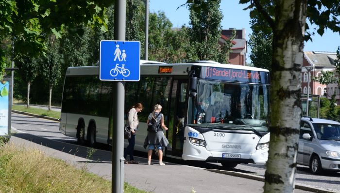 Personer går på bussen på et busstopp