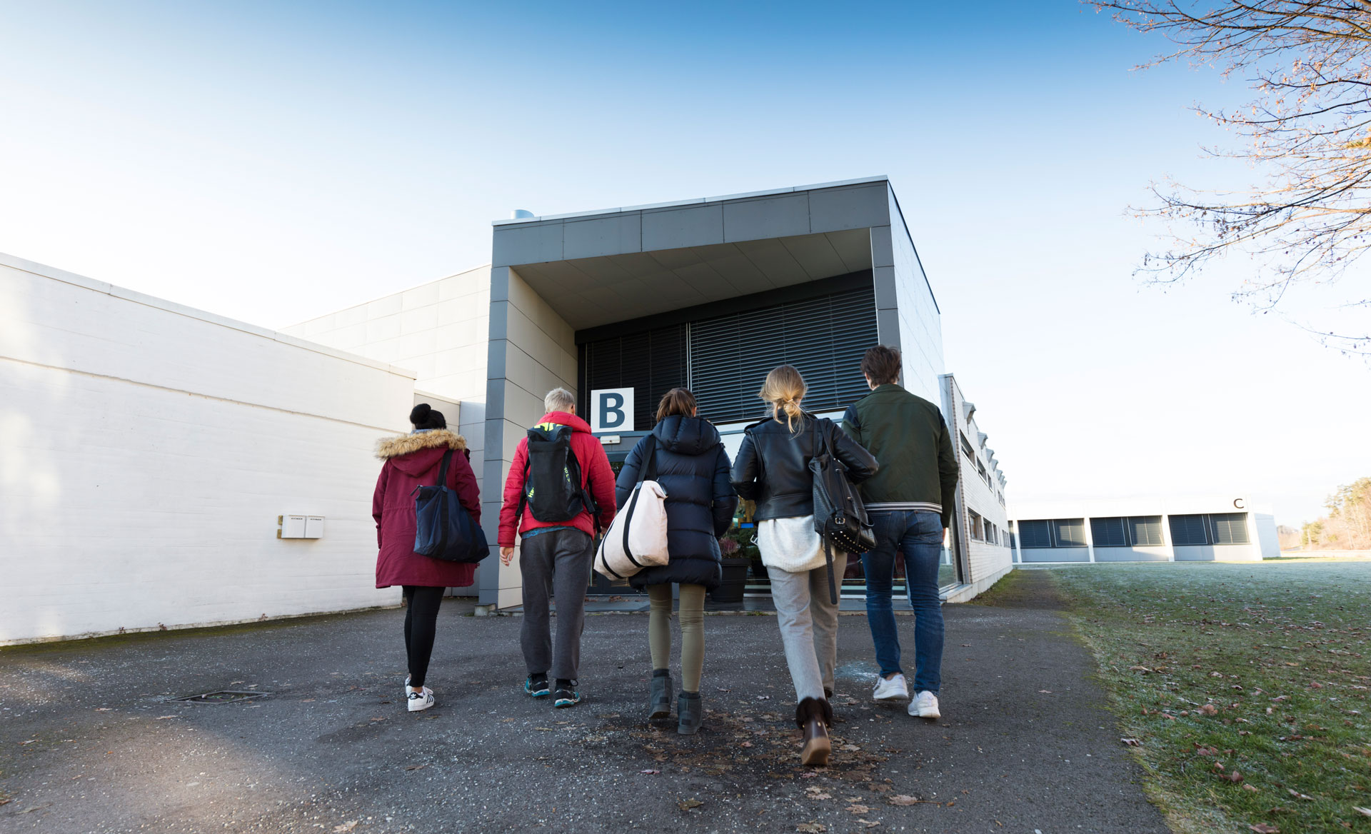 Fire elever går mot et skolebygg