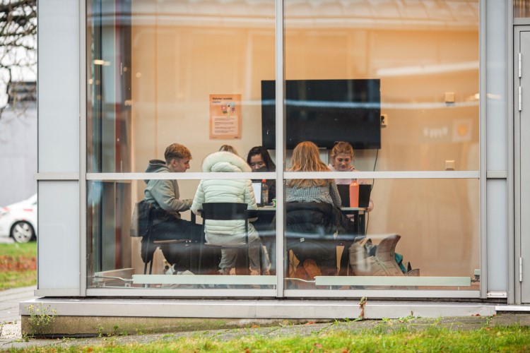 Fem elever sitter rundt et bord og jobber med skolearbeid.