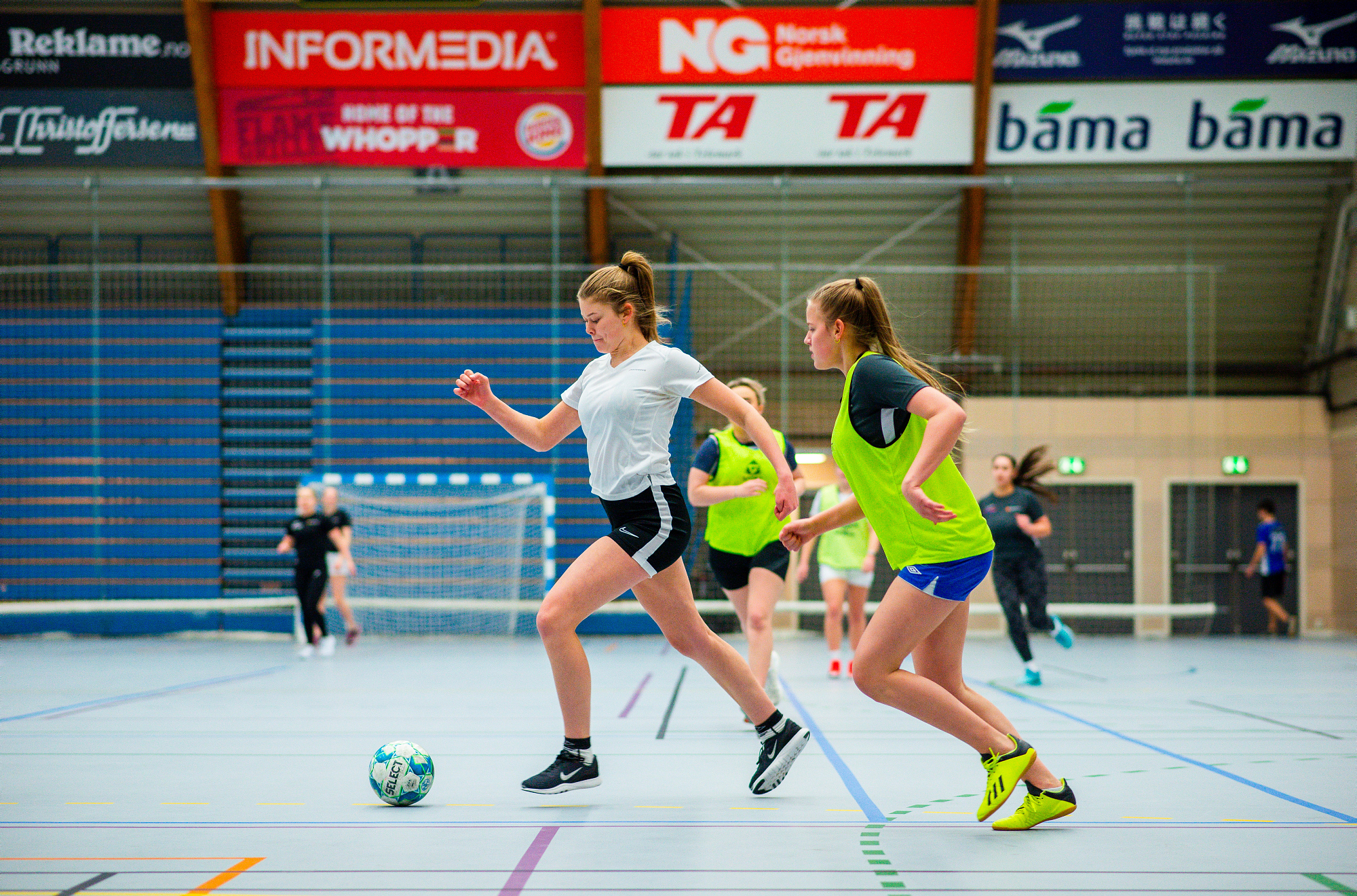 Flere jenter spiller fotball i en hall